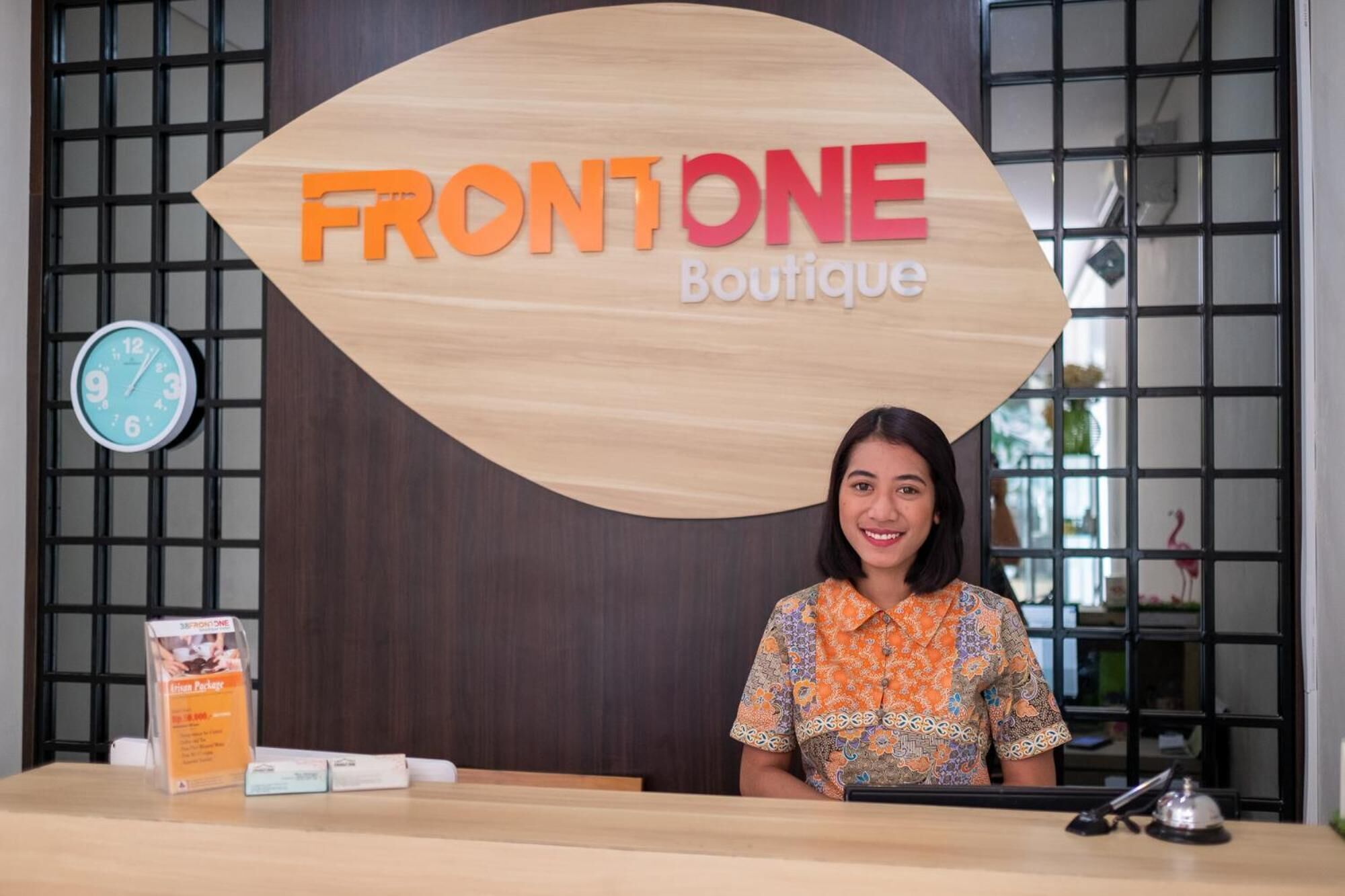 A reception desk with a sign reading "FRONTONE Boutique" and a clock on the wall.