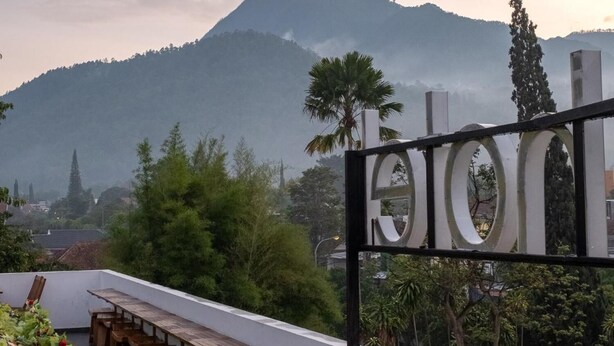 A terrace with wooden benches and a decorative wall, overlooking a mountain and a cityscape. - Three Eight Front One Boutique Batu (Batu)