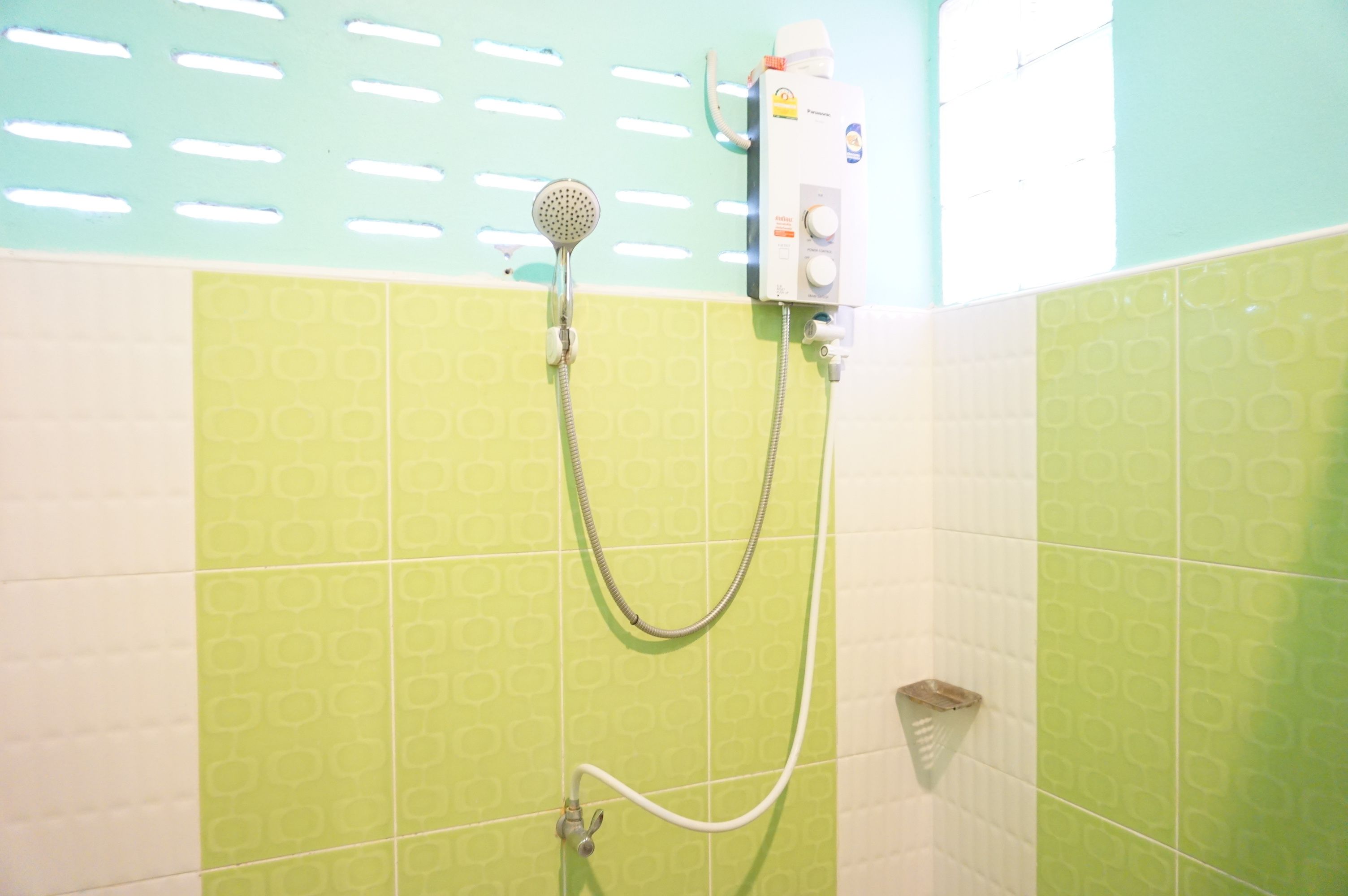 Une douche équipée d’un pommeau de douche à main et d’un panneau de commande fixé au mur.