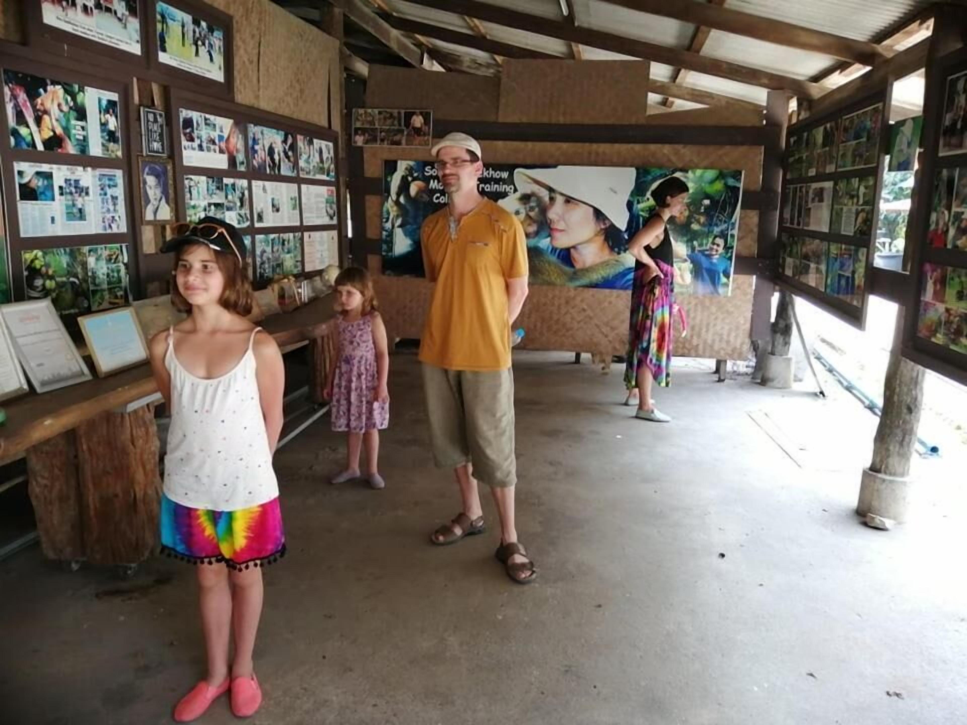 A covered outdoor area with a wooden structure, a concrete floor, and walls adorned with framed pictures.