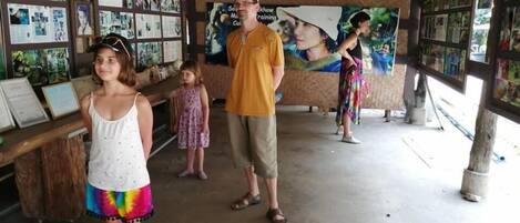A covered outdoor area with a wooden structure, a concrete floor, and walls adorned with framed pictures.