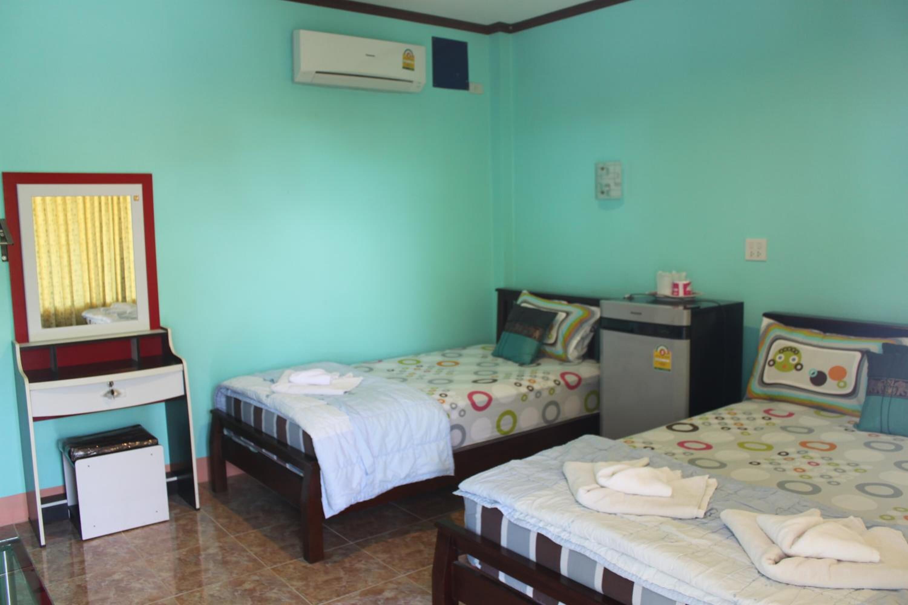 A bedroom with two beds, a desk, and an air conditioning unit.