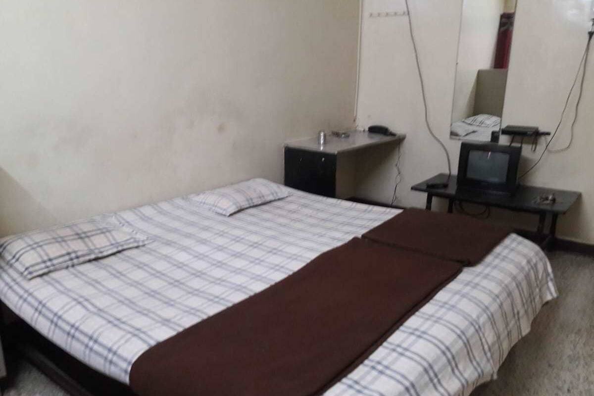 Habitación individual con cama, un pequeño escritorio, una silla y un espejo.