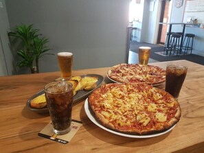 A table with two pizzas, a glass of beer, and a glass of soda. - Riverina Hotel (Holbrook)