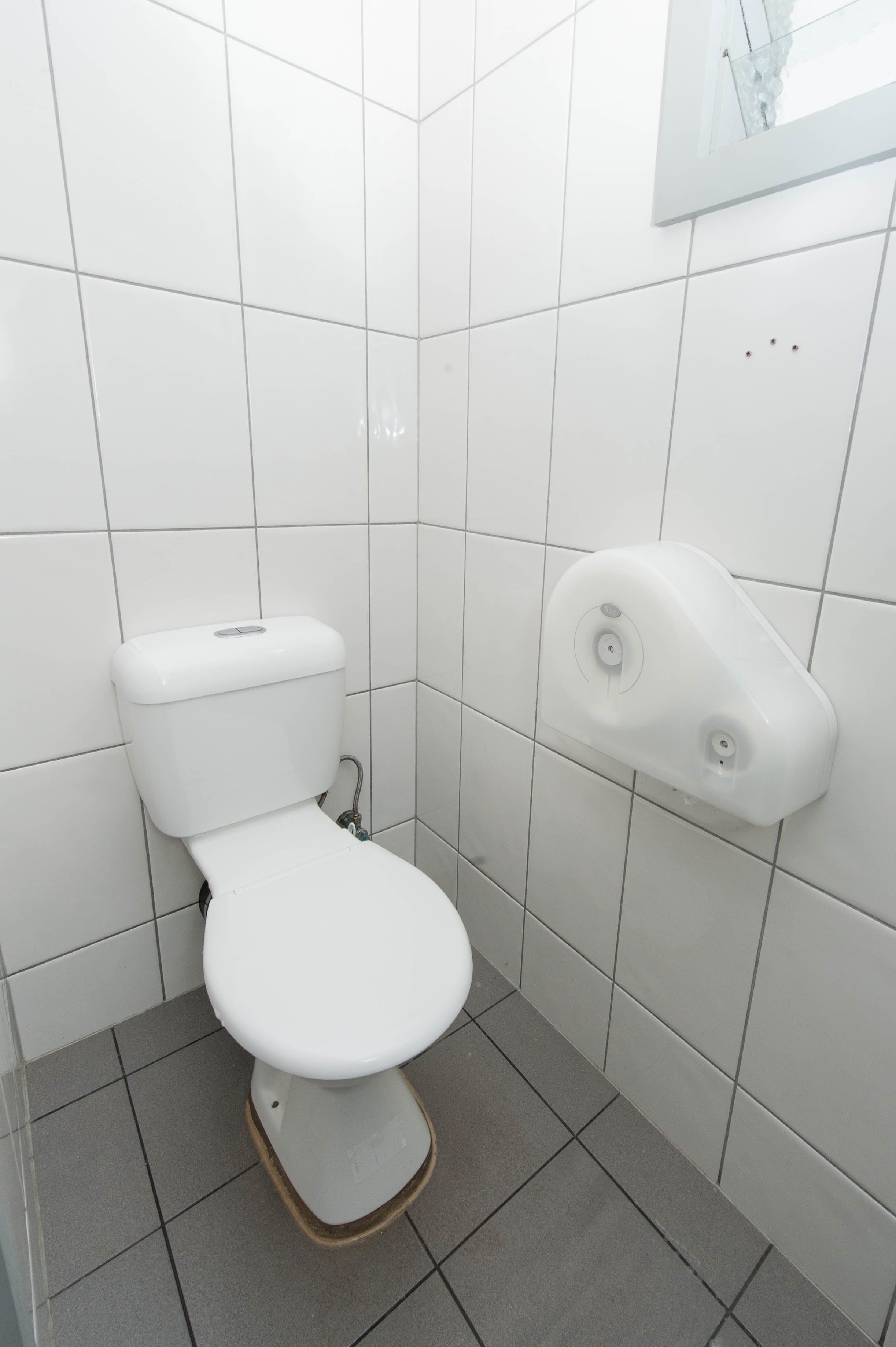A white toilet with a wall-mounted bidet in a tiled bathroom.