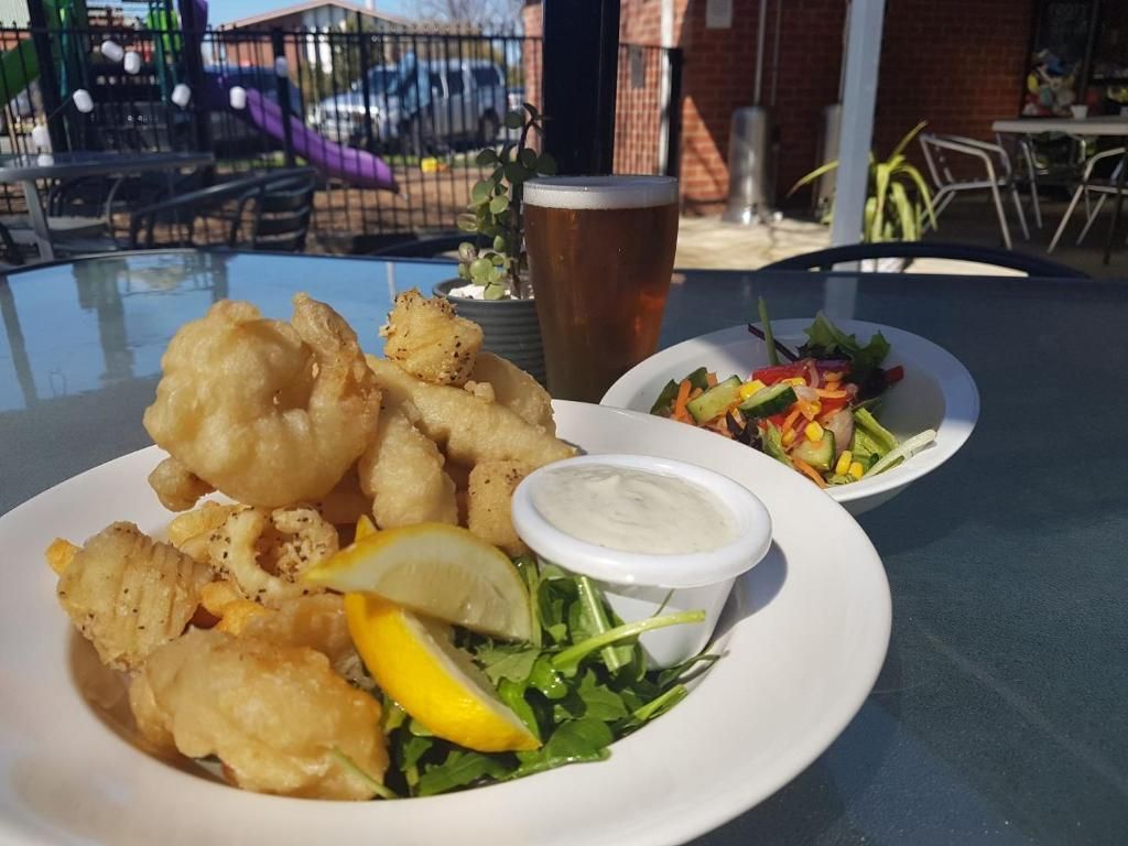 Una comida con frituras, ensalada y una cerveza en una mesa al aire libre.