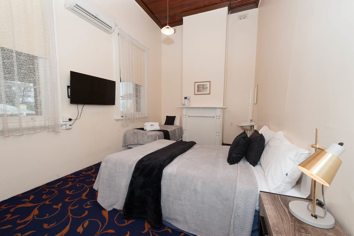 Una habitación de hotel con cama, escritorio, silla, televisión y lámpara.