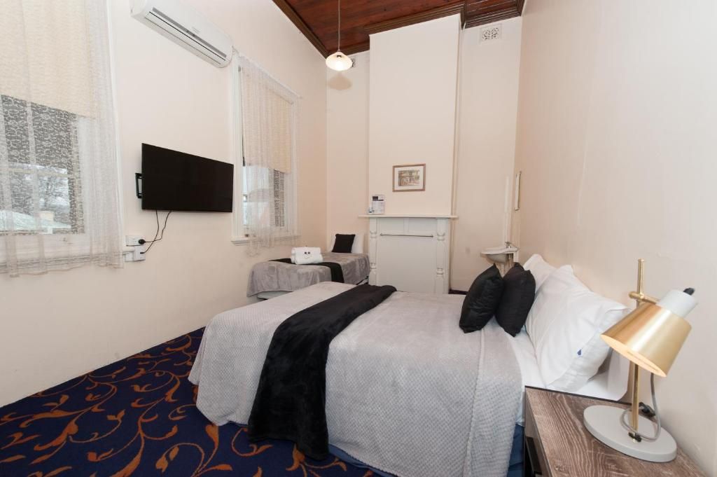 A hotel room with a bed, a desk, a television, and a window.