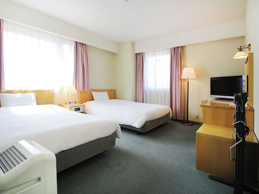 Une chambre d’hôtel avec deux lits, un bureau, une télévision et une lampe.