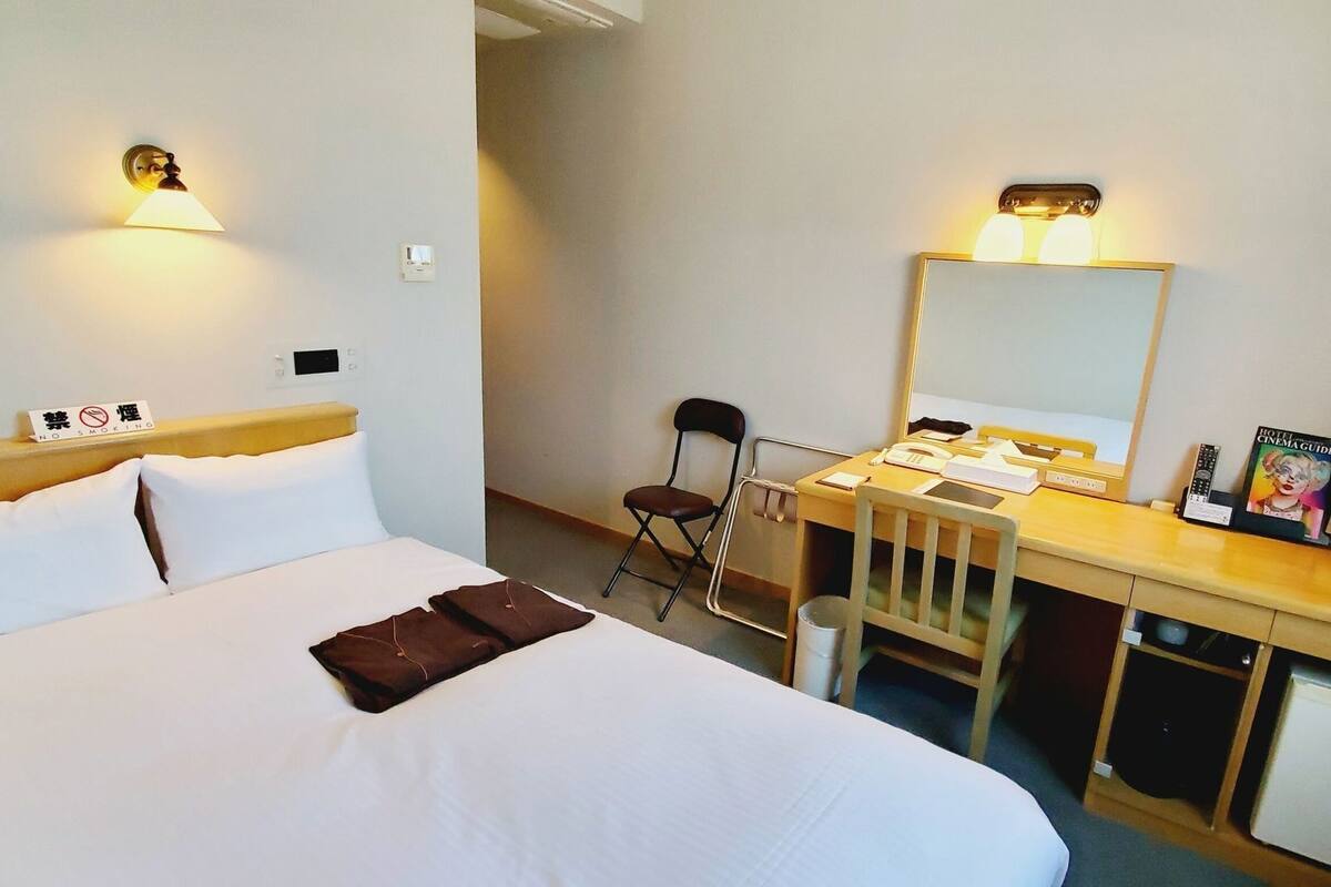 Ein Hotelzimmer mit Bett, Schreibtisch, Stuhl und Spiegel.