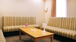Una habitación de hotel con dos sofás a rayas, una mesa de madera y una caja blanca pequeña.