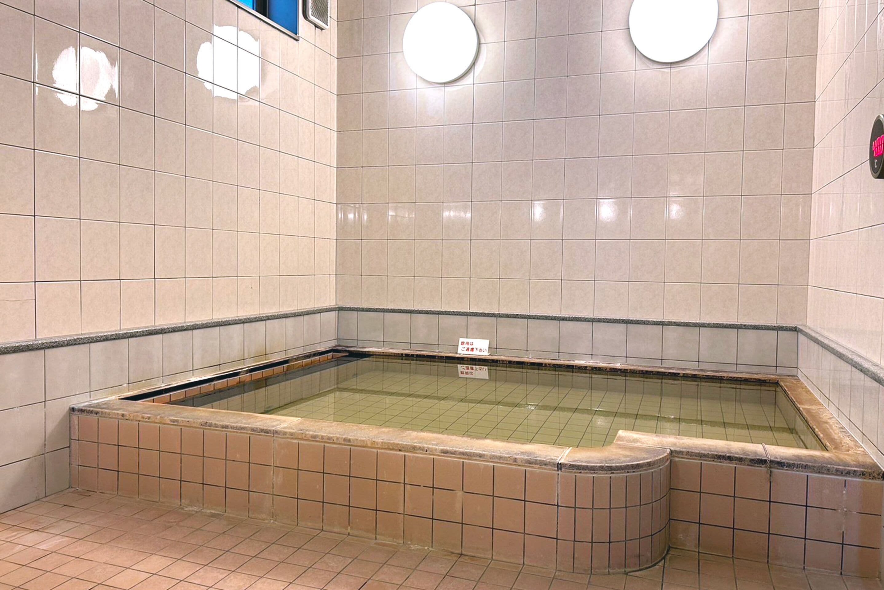 Et offentligt badeområde med flisebelagte vægge og en rektangulær swimmingpool.