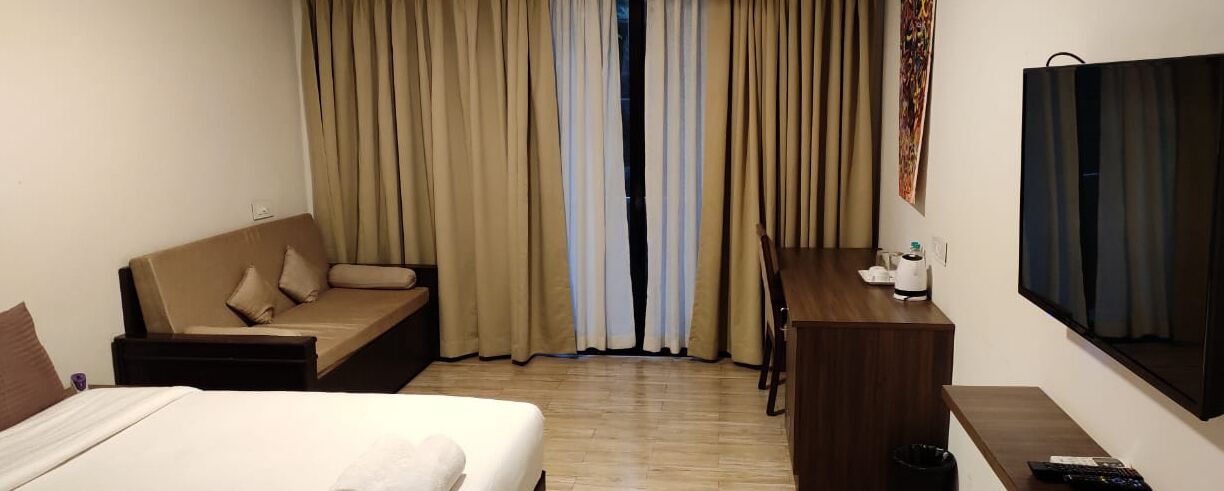 Ein Hotelzimmer mit einem Bett, einer Couch, einem Schreibtisch und einem Fernseher.