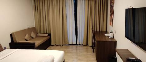 Ein Hotelzimmer mit einem Bett, einer Couch, einem Schreibtisch und einem Fernseher.