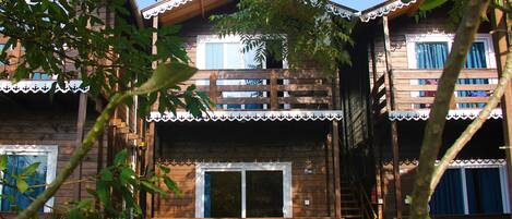 Une cabane en bois dotée d’un balcon, d’un escalier et d’un petit espace porche.