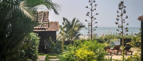 Un jardín tropical con un sendero que lleva a una zona de playa con sillas reclinables.
