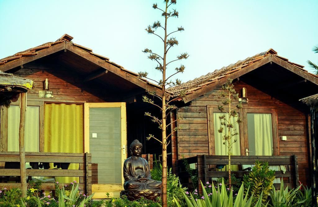 A wooden cabin with a Buddha statue in front.