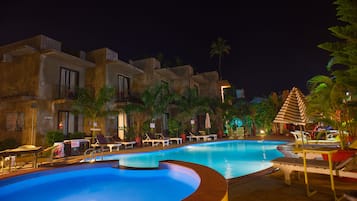 Alberca al aire libre, sombrillas en la alberca y camastros