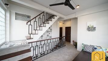 A modern interior with a staircase, ceiling fan, and a sofa with patterned cushions.