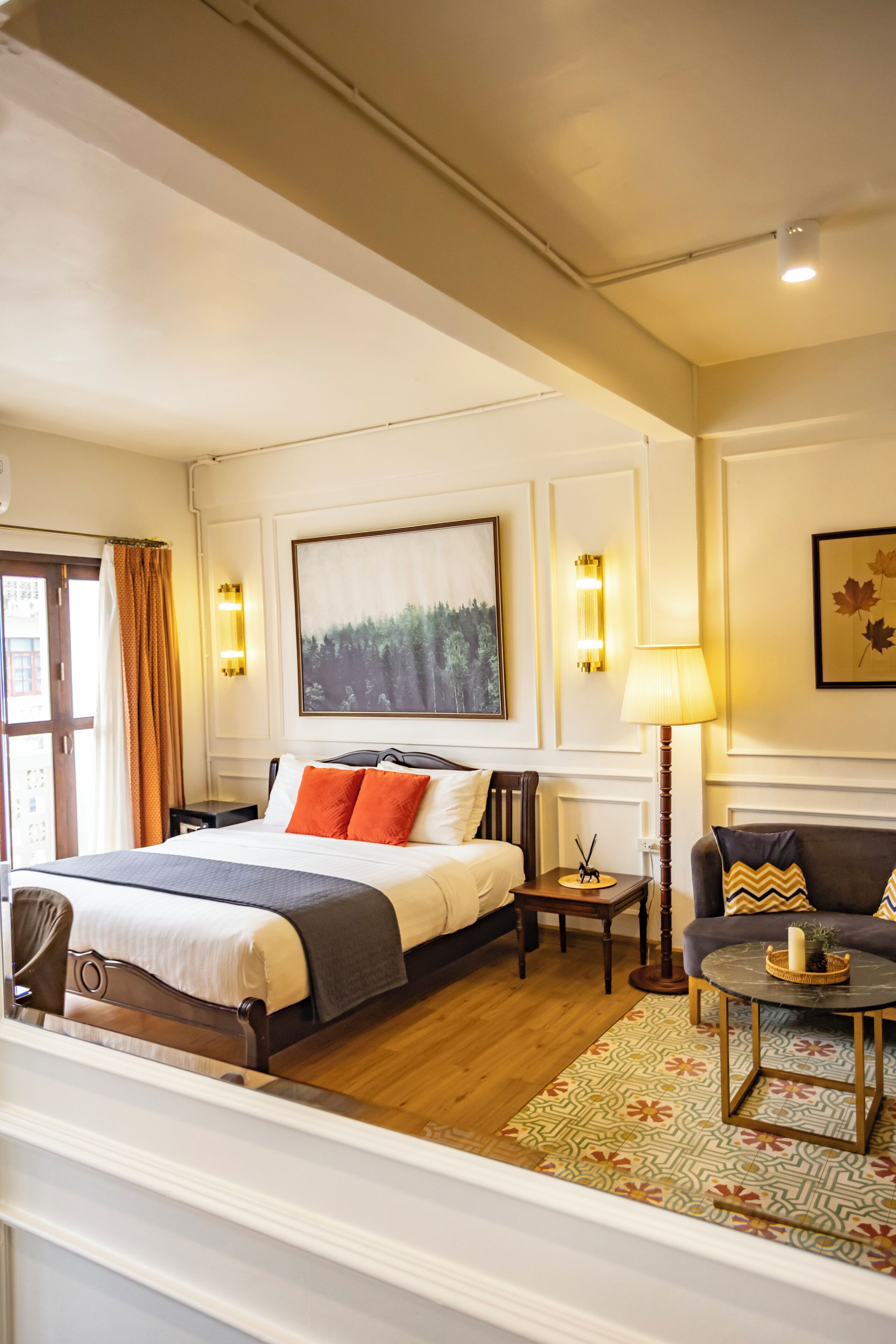 A hotel room with a bed, a sofa, a lamp, and a painting on the wall.
