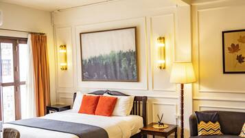 A hotel room with a bed, a sofa, a lamp, and a painting on the wall.