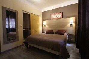 A hotel room with a bed, a mirror, a wardrobe, and two wall-mounted lamps. - Hôtel Le Provencal (Tarascon)