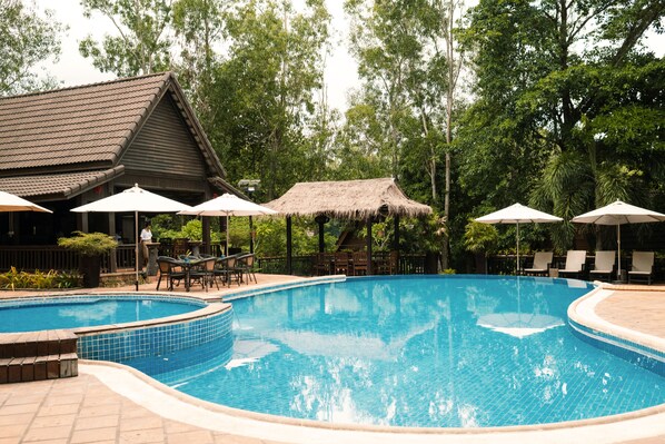 Una piscina al aire libre, sombrillas, tumbonas