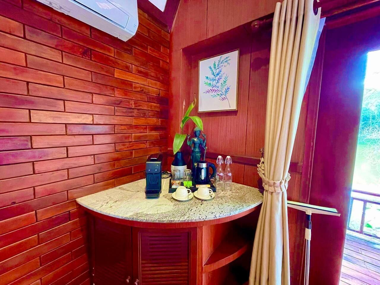 A wooden cabin with a round table set for two, a coffee maker, and a framed plant on the wall.