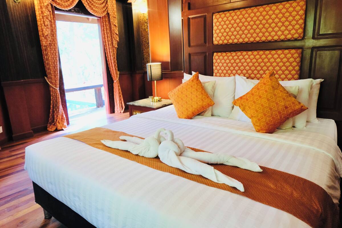 A hotel room with a large bed, two nightstands, a lamp, and a window with curtains.