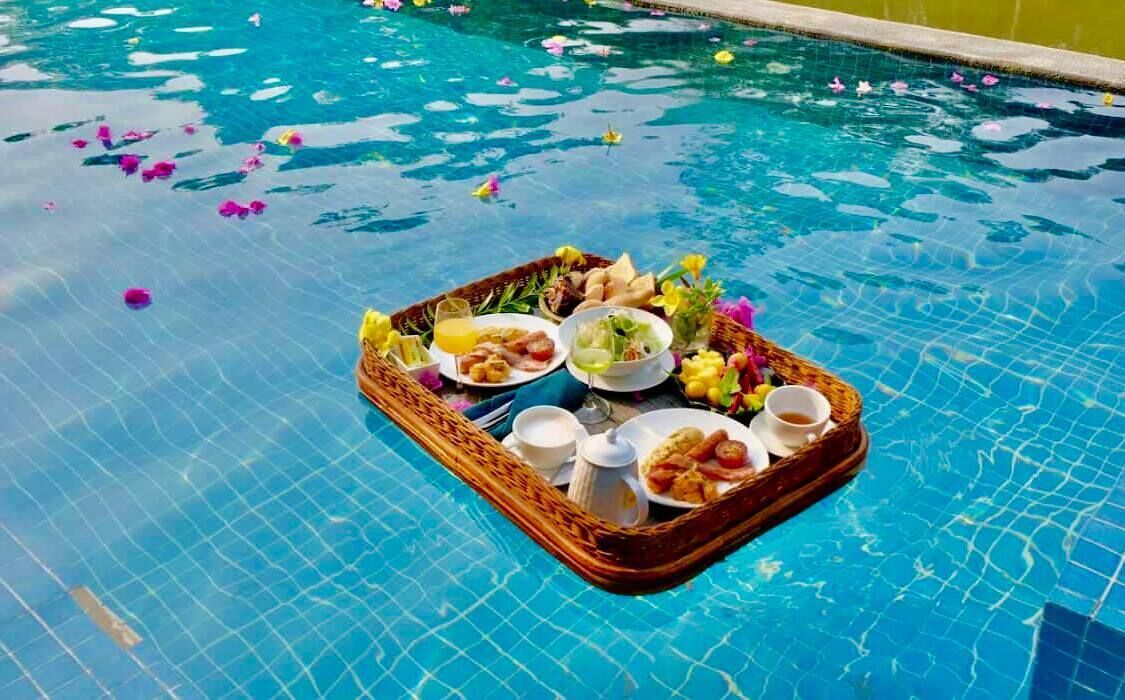 Un petit-déjeuner servi au bord de la piscine, avec un plateau de nourriture et de boissons.