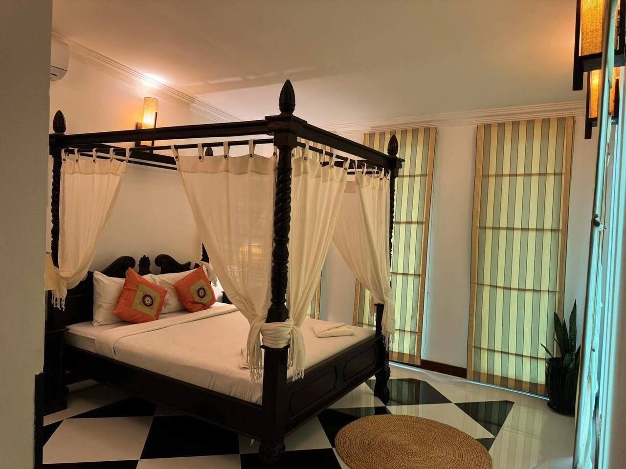 A four-poster bed with a canopy, a checkered floor, and striped curtains.