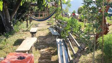 A garden with a hammock, wooden benches, and a picnic table.