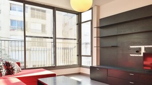 A modern living room with red sofas, a black table, and a dark wooden cabinet. Large windows offer a view of the outside. - Hilton Beach Stunning Designer 2BR APT (Tel Aviv)