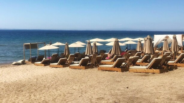 En strand med rader av solstolar och parasoller.