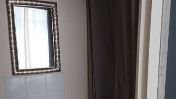 Un bagno con un lavandino bianco, uno specchio con cornice decorativa e una tenda da doccia.