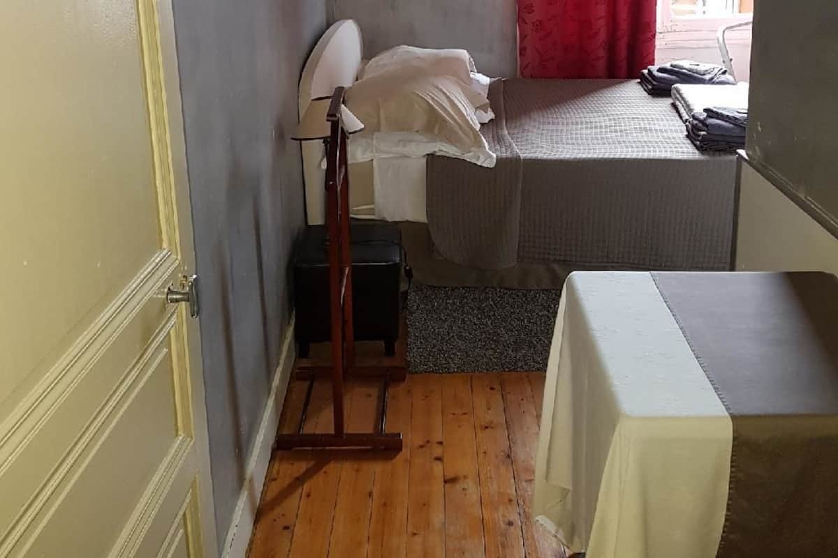 A small, compact room with a bed, a table, and a lamp.