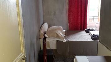 Een kleine, praktische kamer met een bed, een tafel en een lamp.