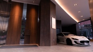A modern building entrance with a BMW sports car parked inside. - Brio Hotel (Kaohsiung)