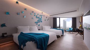 Une chambre d’hôtel moderne avec deux lits, une vue sur la ville et une œuvre d’art murale originale.