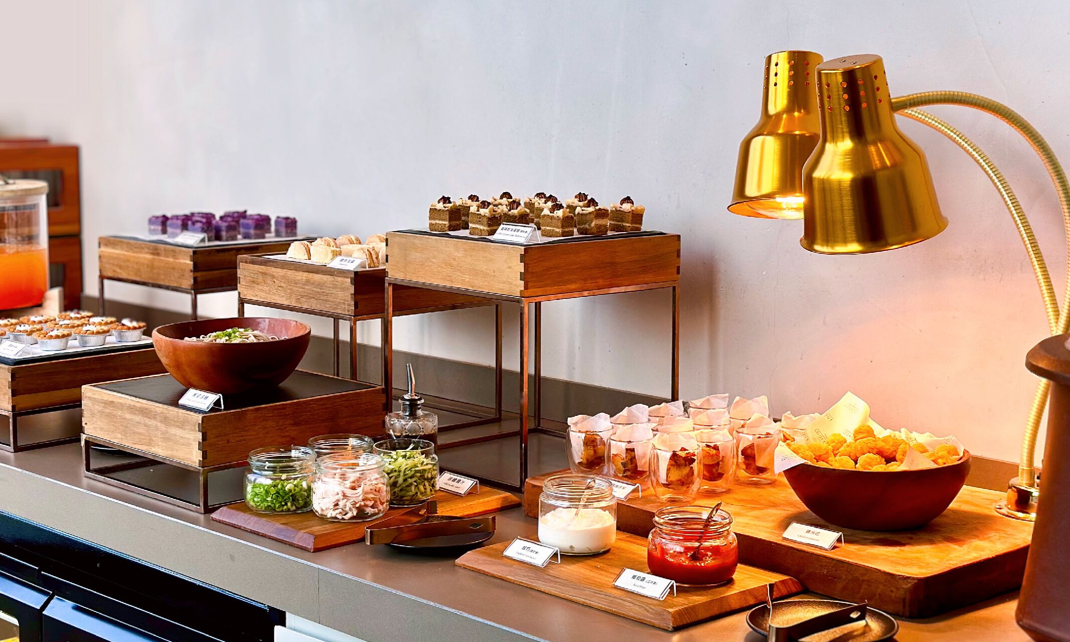A buffet setup with various food items, including pastries, salads, and condiments, arranged on wooden boards and tables.