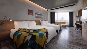 Una camera d'albergo moderna con due letti, una scrivania e vista sulla città.