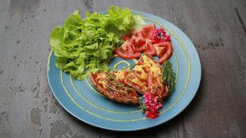 A plate with a slice of quiche, lettuce, and tomato slices on a blue plate.
