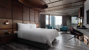 A modern hotel room with a large bed, a desk, and a view of the city. - Brio Hotel (Kaohsiung)