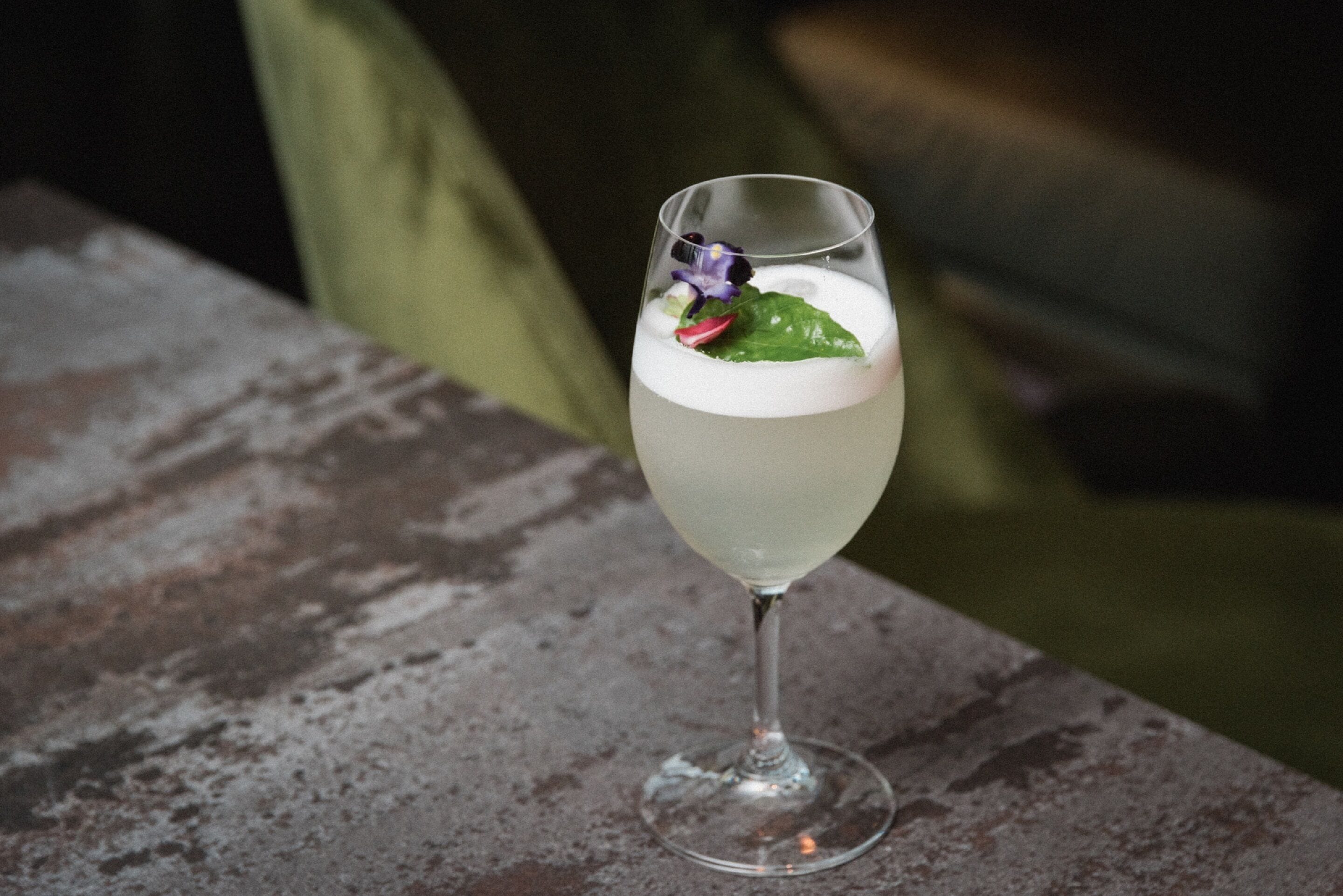 A cocktail in a glass with a garnish on a textured surface.