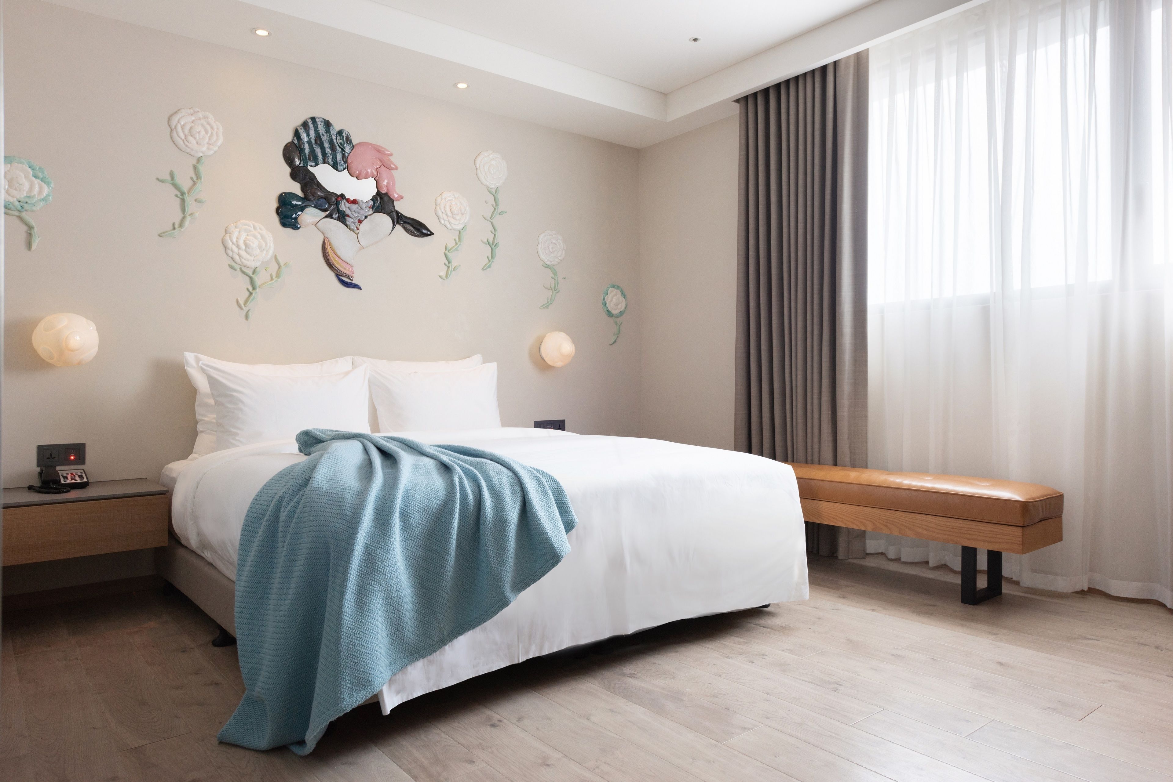 Un dormitorio con cama, un banco y detalles decorativos en la pared.