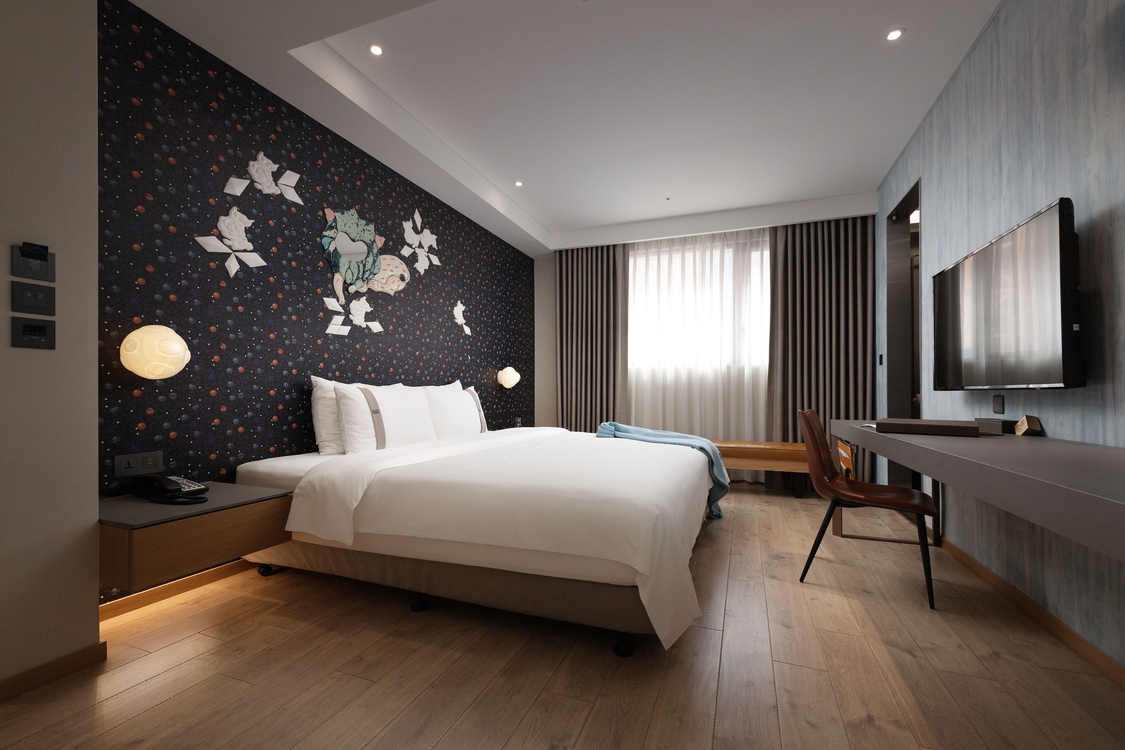 A modern hotel room with a large bed, a desk, and a flat-screen TV.