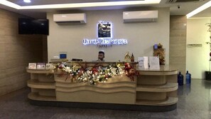A hotel reception desk with a Christmas decoration, a sign reading "Ultima Residences Tower III", and a mounted television. - Super Cebu Loft (Cebu City)