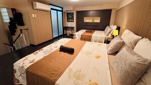 A hotel room with two beds, a desk, a chair, a lamp, and a window. - Super Cebu Loft (Cebu City)