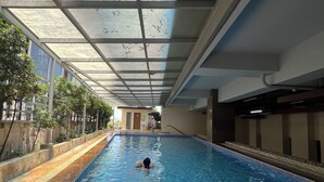 An indoor swimming pool with a tiled floor and a person swimming. - Super Cebu Loft (Cebu City)