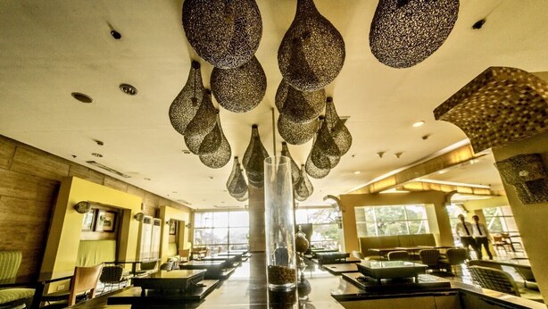 A modern restaurant with a central glass column, hanging decorative light fixtures, and a view of the outdoors. - Super Cebu Loft (Cebu City)